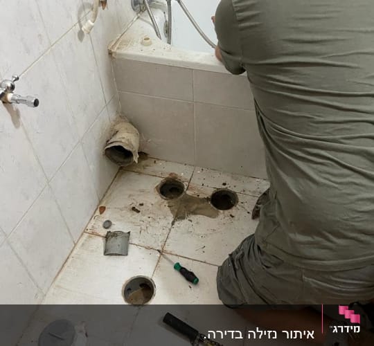 אדם עובד על תיקון צנרת בחדר אמבטיה